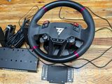 the steering wheel and pedals are on the table next to the game controller