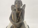 statue of an angel sitting on a stone block holding a staff