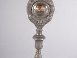 une horloge en argent posée sur un socle surmonté d'une croix