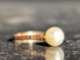 a ring with a pearl on it sitting on a table