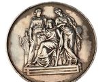 une médaille ancienne en argent représentant une femme et deux hommes sur un piédestal