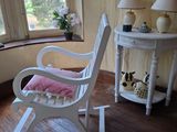 un fauteuil à bascule dans un coin de la pièce, près d'une fenêtre
