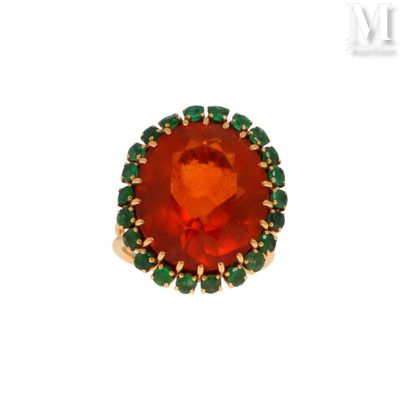 une image représentant une bague ornée d'une pierre rouge entourée de pierres vertes