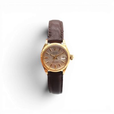 a close up of a watch on a white surface with a brown strap