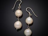 une paire de boucles d'oreilles en perles blanches et argent sur fond noir