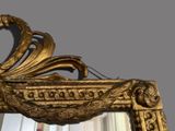 a mirror that has a gold frame with a bird on it