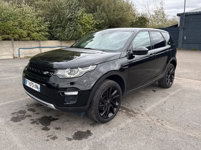 a black land rover parked in a parking lot with trees in the background