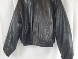 une veste en cuir noir suspendue à un cintre sur un mur blanc