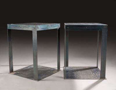 pair of metal side tables on a white surface with a black background