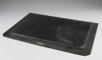 an old black book with a black cover sitting on top of a white table