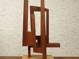 a wooden sculpture on a table with a white wall in the background
