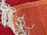a close up of a piece of red carpet with white thread on it
