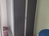 a blue chair sitting in front of a tall cabinet