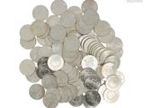 un tas d'argent et de pièces d'argent posé sur une surface blanche
