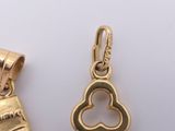 two gold - plated charms of a heart and a book on a white surface