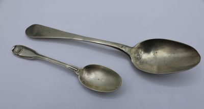 two silver spoons sitting on top of a table next to each other