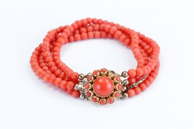 a close up of a bracelet with coral beads on a white background