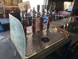 Plusieurs robinets à bière sont alignés sur un comptoir en métal dans un bar