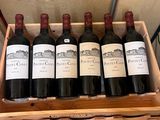 six bottles of red wine in a wooden crate on a table