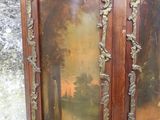 une armoire en bois dont la porte est ornée d'un tableau