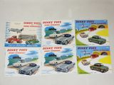 Six camions Dinky Toys différents sont exposés sur une table.