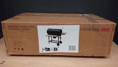 une boîte en carton posée sur une table sur laquelle se trouve un barbecue noir