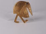 a close up of a gold bird pin on a white surface