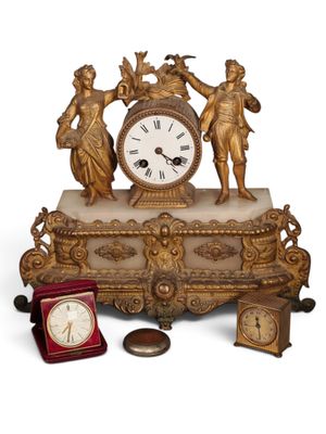a gold clock sitting on top of a table next to other items