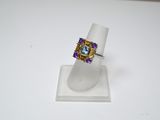 un gros plan d'une bague posée sur un présentoir, sur une surface blanche