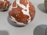 five marble balls sitting on a table with a white background