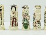 six figurines en ivoire sculpté sont alignées sur une surface blanche