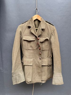 une vieille veste militaire accrochée à un cintre sur un mur