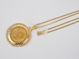 a close up of a gold necklace with a medallion on it