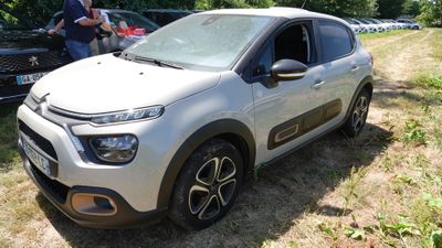 une petite voiture blanche garée sur l'herbe, dans le champ
