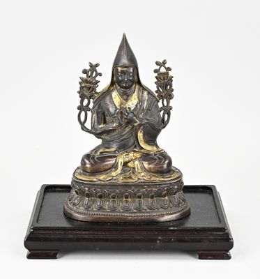 une statue en bronze représentant un Bouddha assis, posée sur un socle en bois