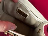 someone is holding a white purse with a gold clasp