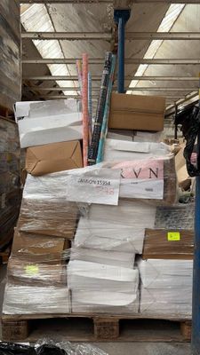 un homme debout à côté d'une pile de cartons dans un entrepôt