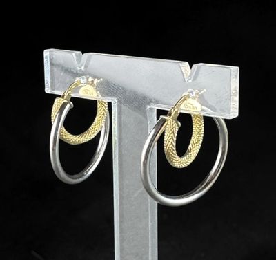 two tone gold and silver hoop earrings on a clear stand