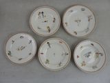 quatre assiettes ornées d'oiseaux et de fleurs sont disposées sur une table