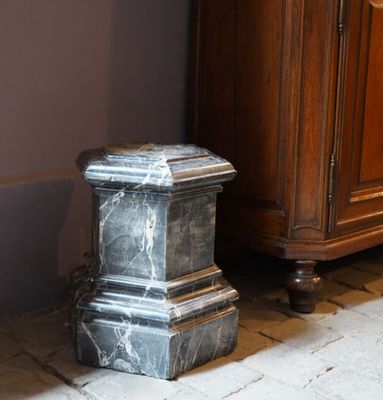 a marble pedestal on the floor next to a cabinet