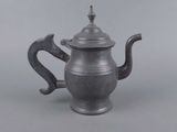 an old silver teapot with a handle on a gray background