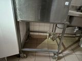 a stainless steel sink in the middle of a tiled floor
