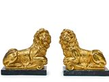 paire de serre-livres en forme de lions en or, posés sur un socle en marbre noir