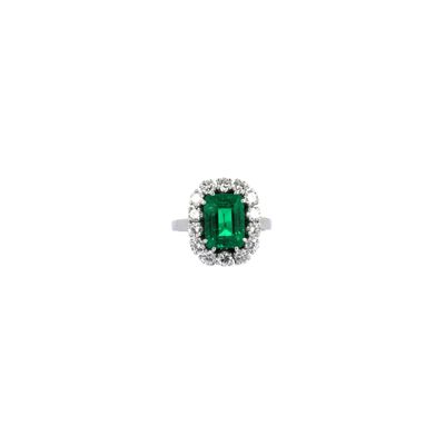 un gros plan d'une bague sertie d'une émeraude verte et de diamants sur fond blanc
