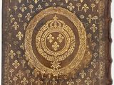 an old book with gold and black designs on a white background