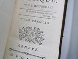 un vieux livre posé sur une table blanche, à côté d'une paire de ciseaux