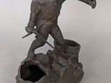 statue of a man with a trumpet on a rock with a hole in the ground