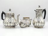 three pieces of silver tea and coffee set on a white surface