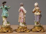 three figurines of women are standing on pedestals on a table