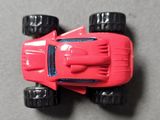 a red toy car with black wheels on a gray surface